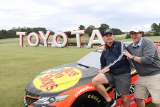 Thumbnail for a group of men posing for a picture next to a race car