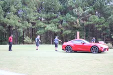 Thumbnail for a group of people standing around a red sports car