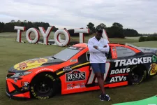 Thumbnail for a person standing next to a race car