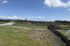 Thumbnail for Construction site with cleared land, grassy area, machinery, and blue sky with clouds on a sunny day