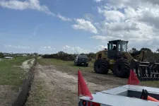 Thumbnail for Construction site with dirt road, heavy machinery, pickup truck, and red safety flags under a cloudy sky