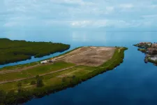 Thumbnail for Aerial view of a waterfront construction site surrounded by water and residential homes under a cloudy sky