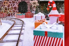 Thumbnail for Festive holiday scene with large wrapped gifts, snow-covered ground, Christmas trees, and a toy train track.