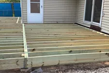 Thumbnail for Wooden deck frame construction attached to a beige house with sliding glass door and white back door