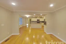Thumbnail for Spacious open floor plan with hardwood floors, beige walls, and modern kitchen with island and mosaic backsplash.