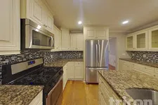 Thumbnail for Modern kitchen with stainless steel appliances, granite countertops, mosaic tile backsplash, and cream cabinetry.