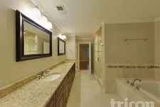 Thumbnail for Spacious bathroom with granite double vanity, framed mirrors, shower, and bathtub with tile accents.