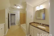Thumbnail for Spacious bathroom with granite countertop vanity, bathtub with tiled wall, and beige walls and flooring.
