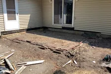 Thumbnail for Backyard area with old brick patio partially removed near beige siding house and sliding glass door