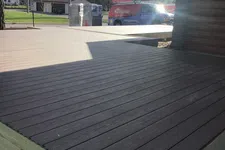 Thumbnail for Newly constructed two-tone wood deck outside a log cabin with a handyman service van in the background.
