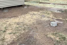 Thumbnail for New wooden deck frame constructed beside house with concrete piers in grassy backyard under construction.