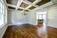 Thumbnail for Empty room with hardwood floors, large windows, coffered ceiling, and chandelier lighting in a modern house.