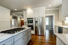 Thumbnail for Modern kitchen with gray island, white cabinets, stainless steel appliances, and hardwood flooring in open layout
