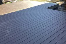 Thumbnail for View of a newly constructed dark wood deck and an unfinished section under construction with a handyman service van nearby.