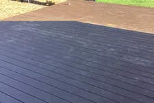 Thumbnail for Two-tone wooden deck patio with black and brown planks under daylight near road and trees.