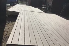 Thumbnail for Newly constructed brown wooden deck extending from a house under a partly cloudy sky.