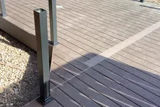 Thumbnail for Newly constructed brown composite wood deck with metal posts for railing under sunlight in outdoor setting.