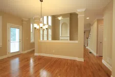 Thumbnail for Empty spacious room with hardwood floors, beige walls, chandelier, ceiling fan, and large windows letting in natural light