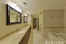 Thumbnail for Spacious bathroom with double sink granite countertop, large mirrors, bathtub, and glass shower enclosure.