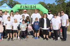 Thumbnail for Group of adults and children in matching shirts standing together at a race finish line outdoors