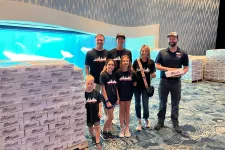 Thumbnail for a group of people posing for a photo in front of a large poster