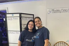 Thumbnail for Two women smiling wearing MaidPro t-shirts standing in front of office whiteboards and chairs.