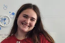 Thumbnail for Smiling young woman in red shirt holding a Canada Dry Ginger Ale Cranberry soda bottle indoors.