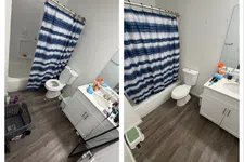 Thumbnail for Two angled views of a clean bathroom with wood-style flooring, white toilet, vanity, and blue-striped shower curtain.