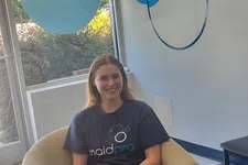 Thumbnail for Smiling woman wearing MaidPro shirt sitting comfortably in an armchair in a professional home cleaning office.