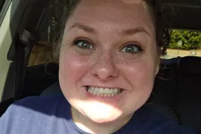 Thumbnail for Smiling woman with freckles wearing a blue shirt with circular patterns sitting inside a car.