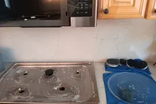 Thumbnail for Clean stainless steel gas stove top and pot lids drying on blue towels in a kitchen with marble backsplash.
