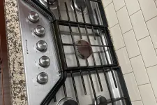 Thumbnail for KitchenAid stainless steel gas stovetop with four burners and control knobs on granite countertop.