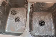 Thumbnail for Dual stainless steel kitchen sinks with soap suds ready for cleaning dishes under bright lighting.