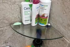 Thumbnail for CeraVe cleanser and Mamaearth shampoo and conditioner bottles on glass shower corner shelves with tiled wall.