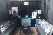 Thumbnail for MaidPro Tacoma booth with couches, pillows, table, plants, and promotional banners at an event