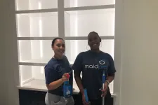 Thumbnail for Two women in Maid Pro shirts holding cleaning supplies in a modern, empty white shelving area.