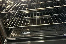 Thumbnail for Clean, empty oven interior with metal racks and a light illuminated inside.
