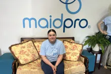 Thumbnail for MaidPro employee sitting on floral couch under MaidPro logo in a clean, welcoming office space.
