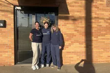 Thumbnail for Three women in MaidPro uniforms standing outside a brick building entrance with a wreath on the door.
