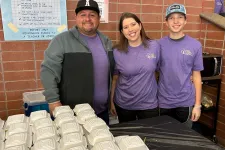 Thumbnail for a group of people standing next to a table with white containers