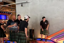 Thumbnail for Group of adults wearing kilts playing indoor mini golf in a colorful, modern entertainment venue.