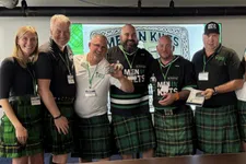 Thumbnail for Group of men and women wearing green tartan kilts posing at a Men in Kilts event with smiles and awards.