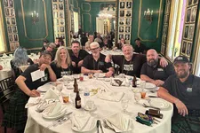 Thumbnail for Group of men and women wearing kilts seated around a table in an ornate green and gold dining room.