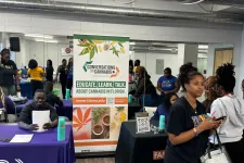 Thumbnail for People attending an educational cannabis event with informational tables and promotional banners indoors.