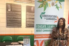 Thumbnail for Woman standing next to a cannabis education booth with informational banner and brochures in a public space.