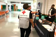 Thumbnail for American Red Cross Disaster Relief volunteer walking towards an information booth in a large indoor space.