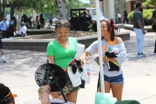 Thumbnail for Two young women smiling and holding promotional materials at an outdoor event on a sunny day