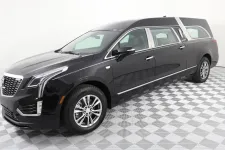 Thumbnail for A sleek black Cadillac hearse showcased on a patterned floor in a studio setting.