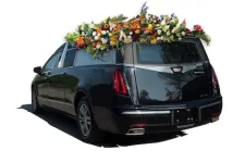 Thumbnail for A hearse adorned with vibrant flowers, showcasing floral arrangements atop a sleek black vehicle.