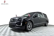 Thumbnail for Black Cadillac hearse with American flags, showcasing elegance and professionalism in funeral vehicles.